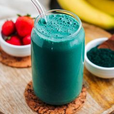 a smoothie in a glass with strawberries on the side