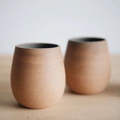 two brown vases sitting on top of a wooden table