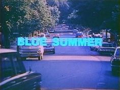 cars driving down the road in front of trees and bushes with blue text reading blue summer