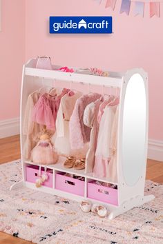 a child's closet with pink drawers and clothes hanging on the wall next to a mirror