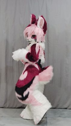 a pink and white stuffed animal standing on its hind legs