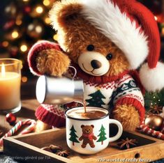 a teddy bear in a santa hat is pouring hot chocolate into a mug with a lit candle