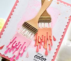 a close up of a card with paint dripping on it and a wooden spatula