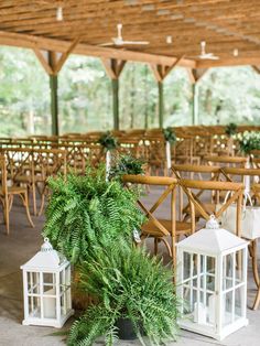 two white lanterns are sitting on the ground in front of tables with chairs and plants