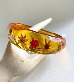 Gorgeous & becoming rare,  Art Deco 1930s reverse carved bakelite bangle In translucent, apple juice Bakelite which is asymmetrical in shape  Reverse carved to the thicker side with flowers & leaves design  looks lovely when it catches the light , almost glows , quite stunning ! Test Positive for Bakelite  bracelet size : Graduating from 1" (2.4 cm)  at widest part  down to 3/8" (0.8cm)  2 & 1/2 " (6.5cm)  internal diameter  In great vintage condition , very light surface wear commensurate  (ver Vintage Resin Bracelet, Vintage Bakelite Bangle Jewelry, Vintage Bakelite Bangle, Vintage Carved Orange Jewelry, Orange Carved Vintage Jewelry, Vintage Lucite Bangle Bracelet, Vintage Orange Carved Jewelry, Vintage Yellow Resin Jewelry, Vintage Amber Resin Jewelry