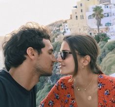 a man and woman standing next to each other near the ocean