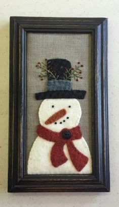 a snowman with a hat and scarf is in a framed frame on the wall