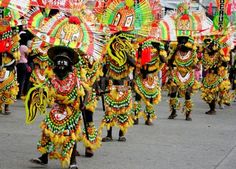 a group of people in colorful costumes walking down a street with umbrellas on their heads