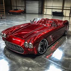 a shiny red car is parked in a garage