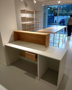 a white desk and shelves in a room with a man looking out the window behind it