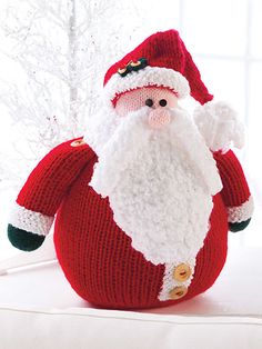 a knitted santa clause sitting on top of a bed