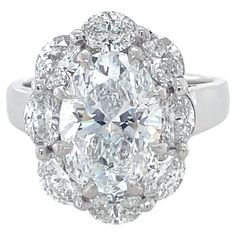 This stunning ring features a 3.03 carat D/SI2 oval brilliant cut diamond surrounded by eight oval brilliant cut diamonds weighing approximately 1.62 carats total. Skillfully crafted in platinum with claw prongs around the center diamond, this ring is sure to make heads turn. Ring Size: 6 1/2. Metal: Platinum. Stamp: PLAT. Gross weight: 9.84 dwt. GIA, 2022, Report No. 6422086567, 3.03 carats, D color, SI2 clarity, Faint fluorescence Emerald Cut Diamond Engagement, Contemporary Engagement Rings, Three Stone Diamond Ring, Modern Engagement Rings, Engagement Ring Diamond Cut, Three Stone Diamond, Diamond Cocktail Rings, Three Stone Engagement, Modern Ring