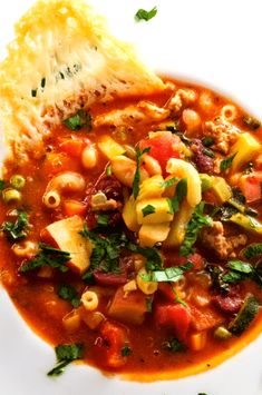 a white plate topped with pasta and meat soup next to a piece of broccoli