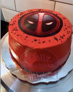 a red cake with black sprinkles and a deadpool face on top