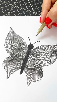 a woman's hand holding a pencil drawing a butterfly