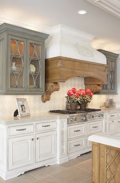 a kitchen with white cabinets and flowers on the stove top, in front of an oven