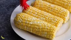 two corn cobs on a white plate with the words brush with oil over them