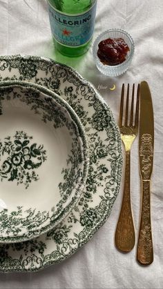 a table set with plates, silverware and condiments on top of a white cloth