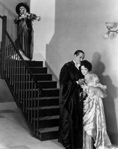 an old black and white photo of a man and woman standing in front of stairs