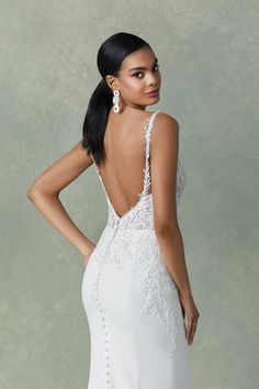 a woman in a white wedding dress with an open back and beaded details on the side