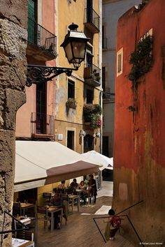 an alleyway with tables and umbrellas next to buildings in the old part of town