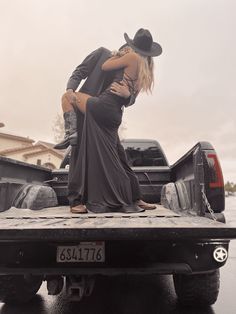 a man and woman kissing in the back of a pickup truck