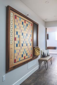 a board game is hanging on the wall next to a chair and ottoman in a room