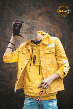 a man wearing a yellow jacket and holding a cell phone up to his face while standing in front of a wall