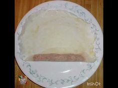 a white plate topped with meat on top of a wooden table