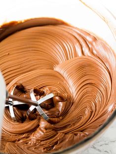 a mixing bowl filled with chocolate frosting on top of a counter