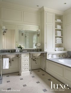 a large bathroom with two sinks and a bathtub in the middle is decorated in white