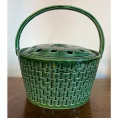 a green basket sitting on top of a wooden table