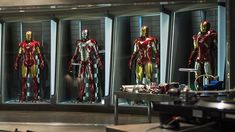 several iron man costumes are displayed in glass cases