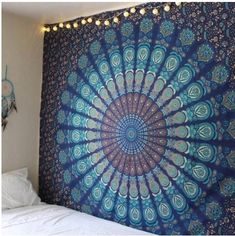 a large blue tapestry hanging on the side of a wall next to a white bed