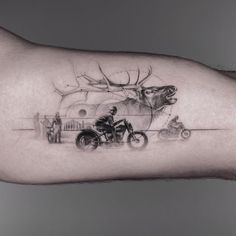 a man's arm with a deer and motorcycle tattoo on it