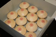 twelve cupcakes in a box with frosting and pink decorations on the top