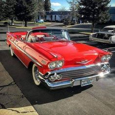 an old red car parked in a parking lot