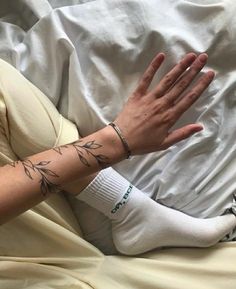 a person laying in bed with their hand on top of the pillow and arm tattoo