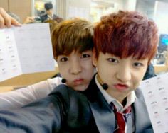 two boys in suits and ties are holding up some papers with writing on them as they look at the camera