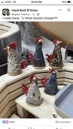 a group of ceramic roosters sitting on top of a table next to each other