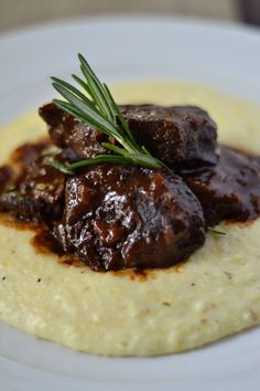 a plate with some meat and gravy on top of mashed grits