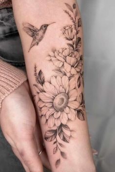 a woman's arm with flowers and a hummingbird on the left side of her arm