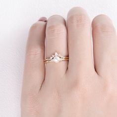 a woman's hand wearing a gold ring with pearls on the band and a diamond in the middle