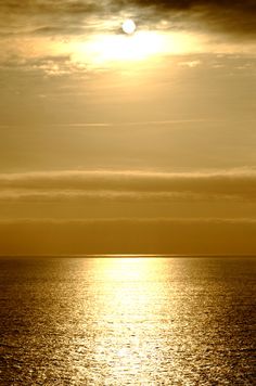 the sun is setting over the ocean with some clouds in the sky and one lone boat out on the water