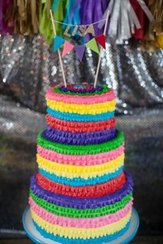 a multi - colored cake on a table with streamers and tassels around it