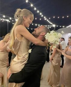 a man in a tuxedo is being hugged by a woman on the dance floor