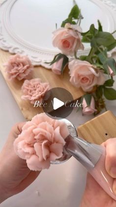 someone is using a pair of scissors to cut pink flowers on a wooden cutting board