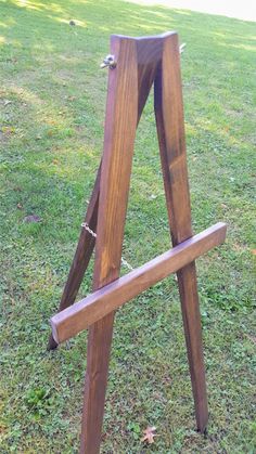 a wooden easel sitting on top of a grass covered field next to a tree