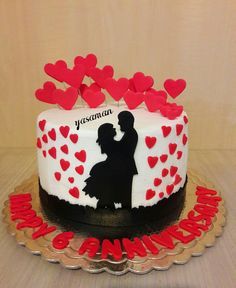 a cake decorated with red hearts and a silhouette of a man and woman