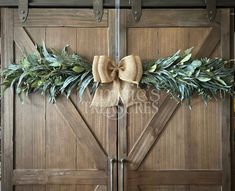 a wooden door decorated with greenery and a bow